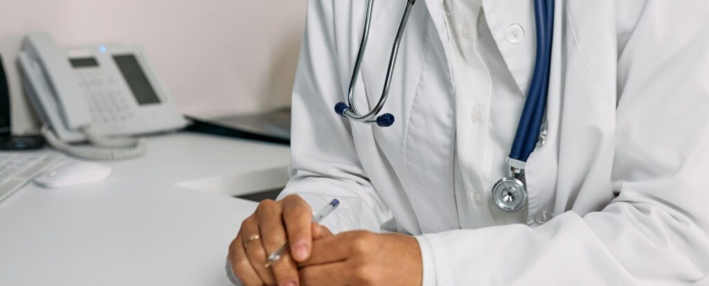 Doctor in white coat with stethoscope at a desk in a French medical office