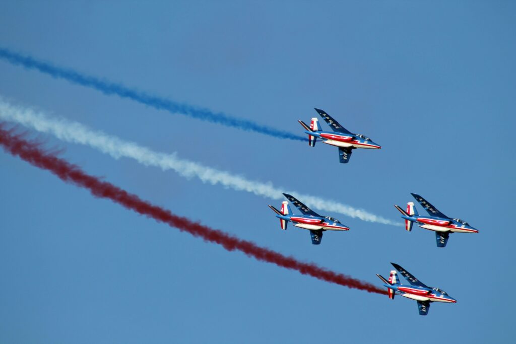 French Air Force aerobatic team flying over the July 14th military parade with blue, white, and red smoke trails